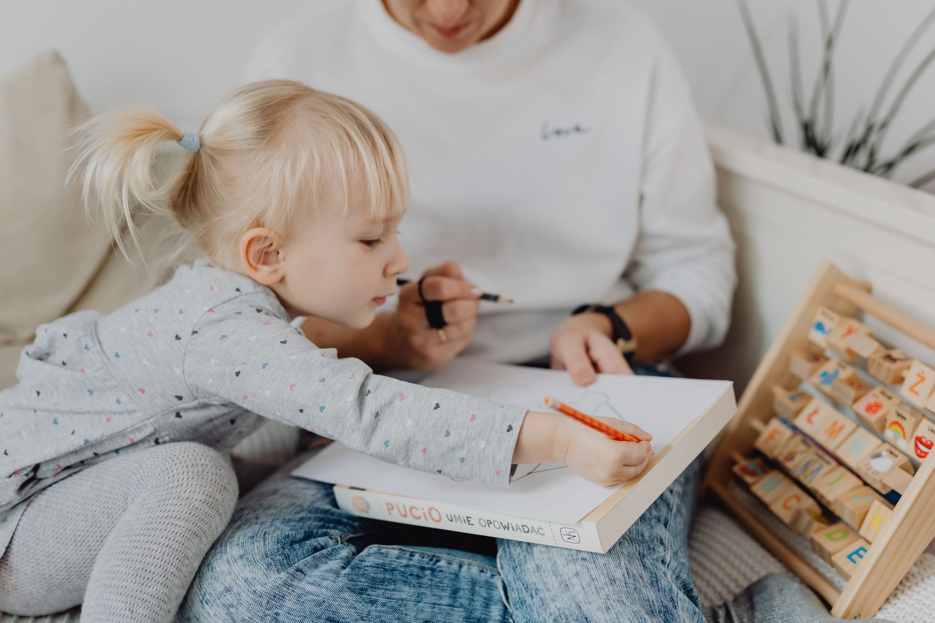 Mother and young daughter bonding over drawing activities at home, fostering creativity.